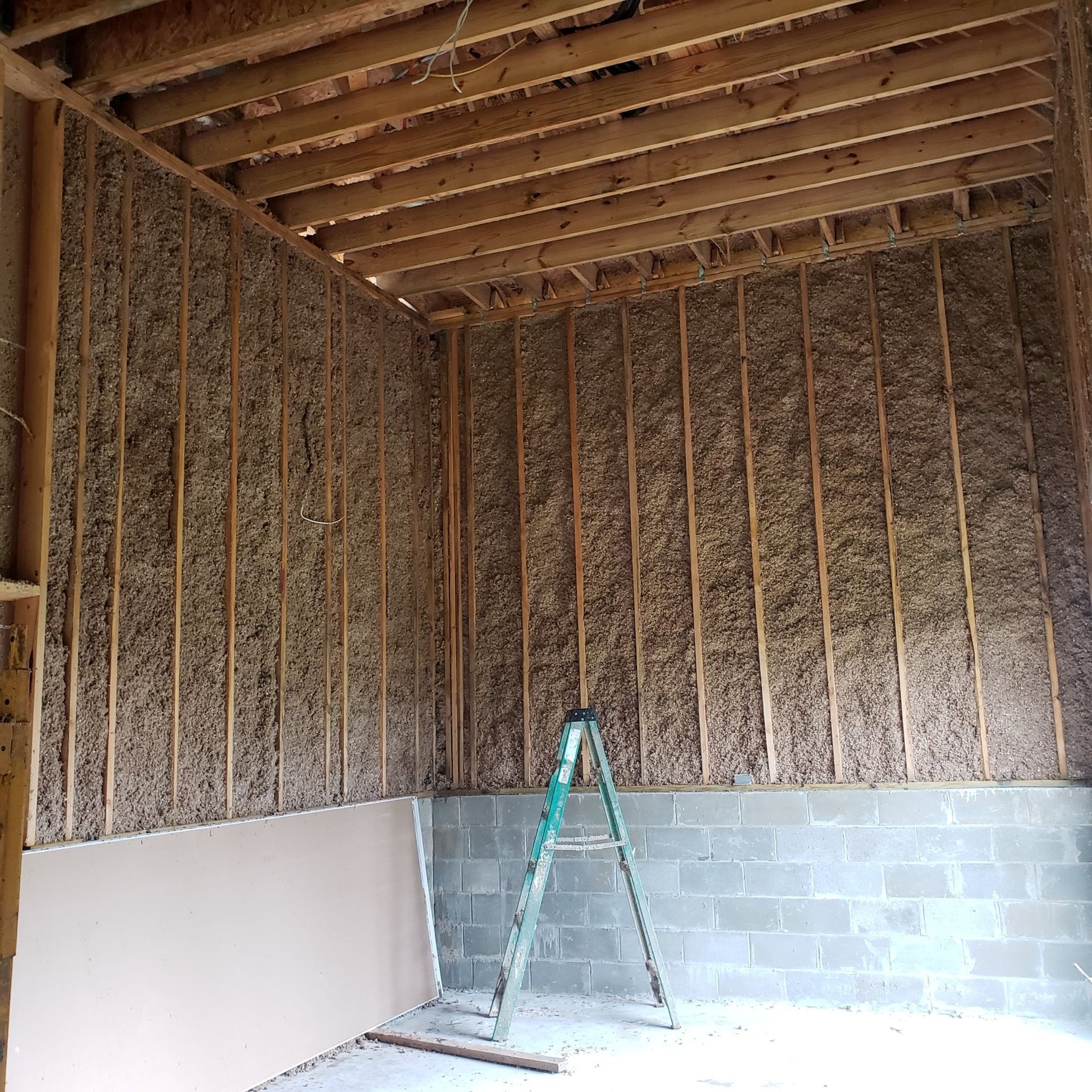 A ladder is sitting in the middle of a room under construction.