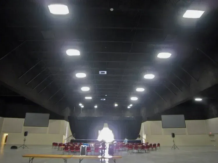 A large auditorium with rows of chairs facing a stage illuminated by a bright, glowing center light.