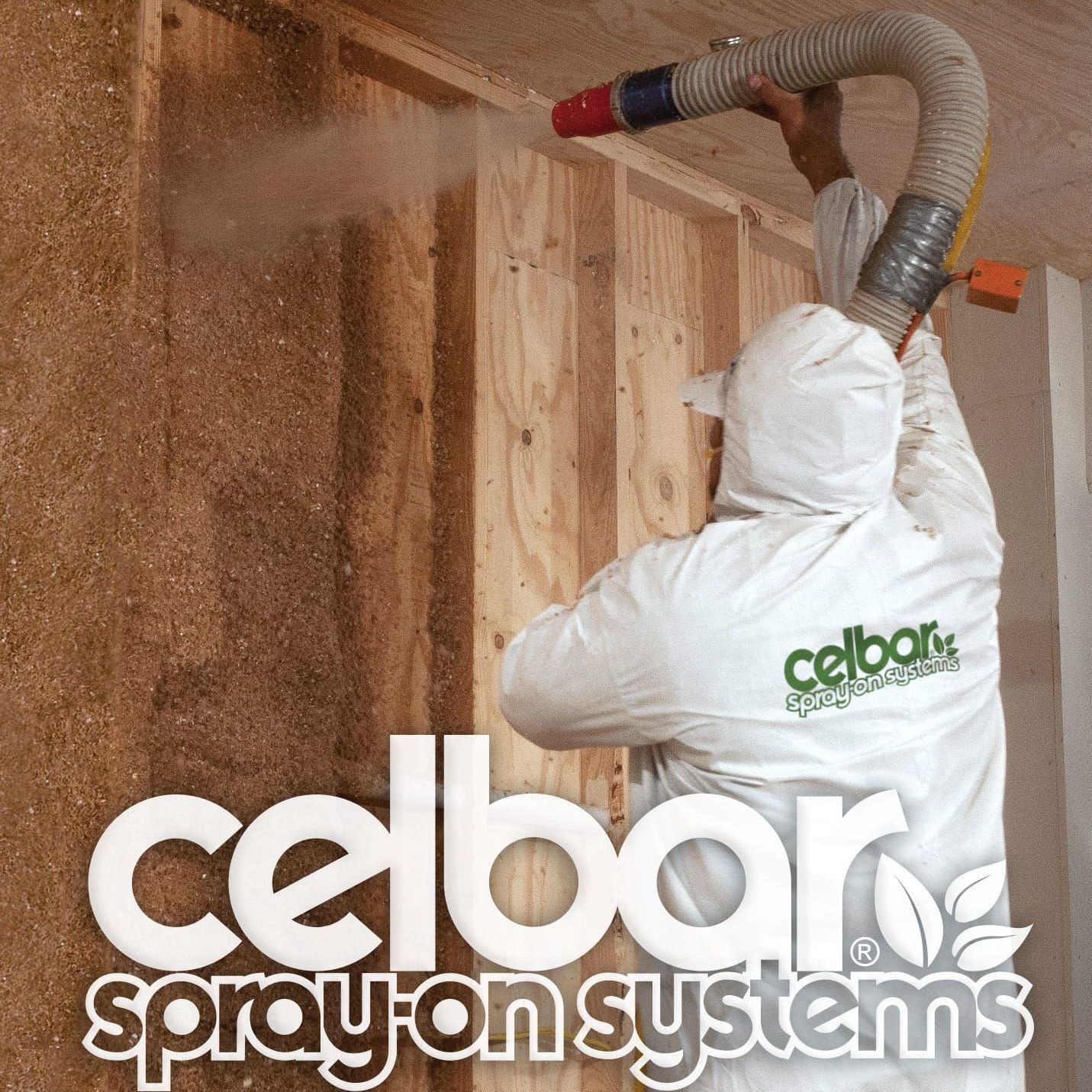 A person in white protective gear sprays Celbar insulation into the wall studs of an unfinished room.