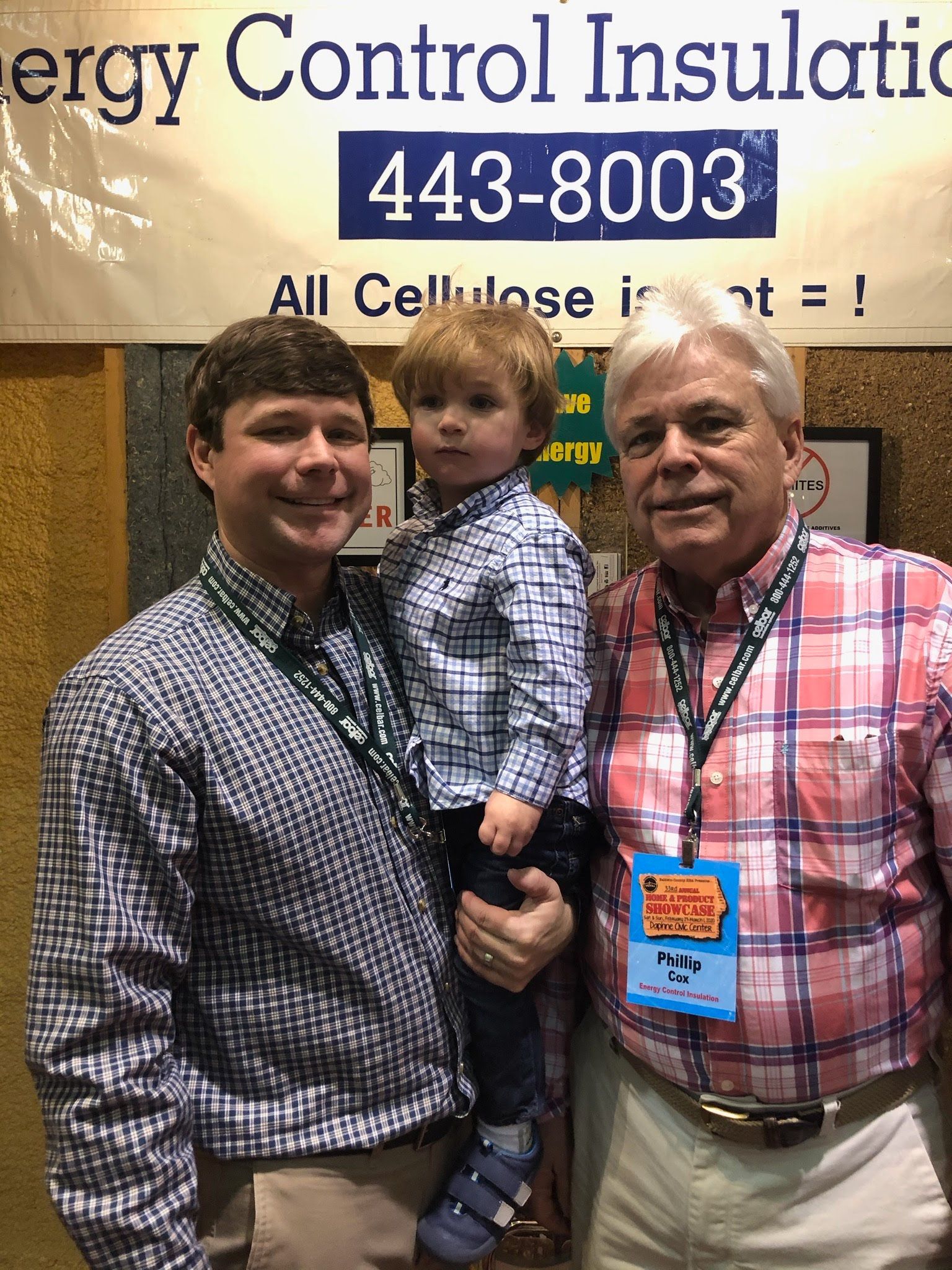 Three people stand in front of a banner for Energy Control Insulation, wearing collared shirts and name-tag lanyards.