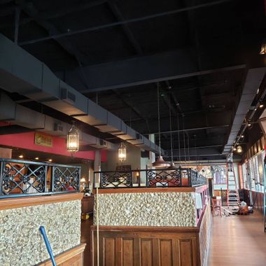 A restaurant interior featuring dark industrial ceilings, decorative dividers with gold-patterned walls, and warm lighting.