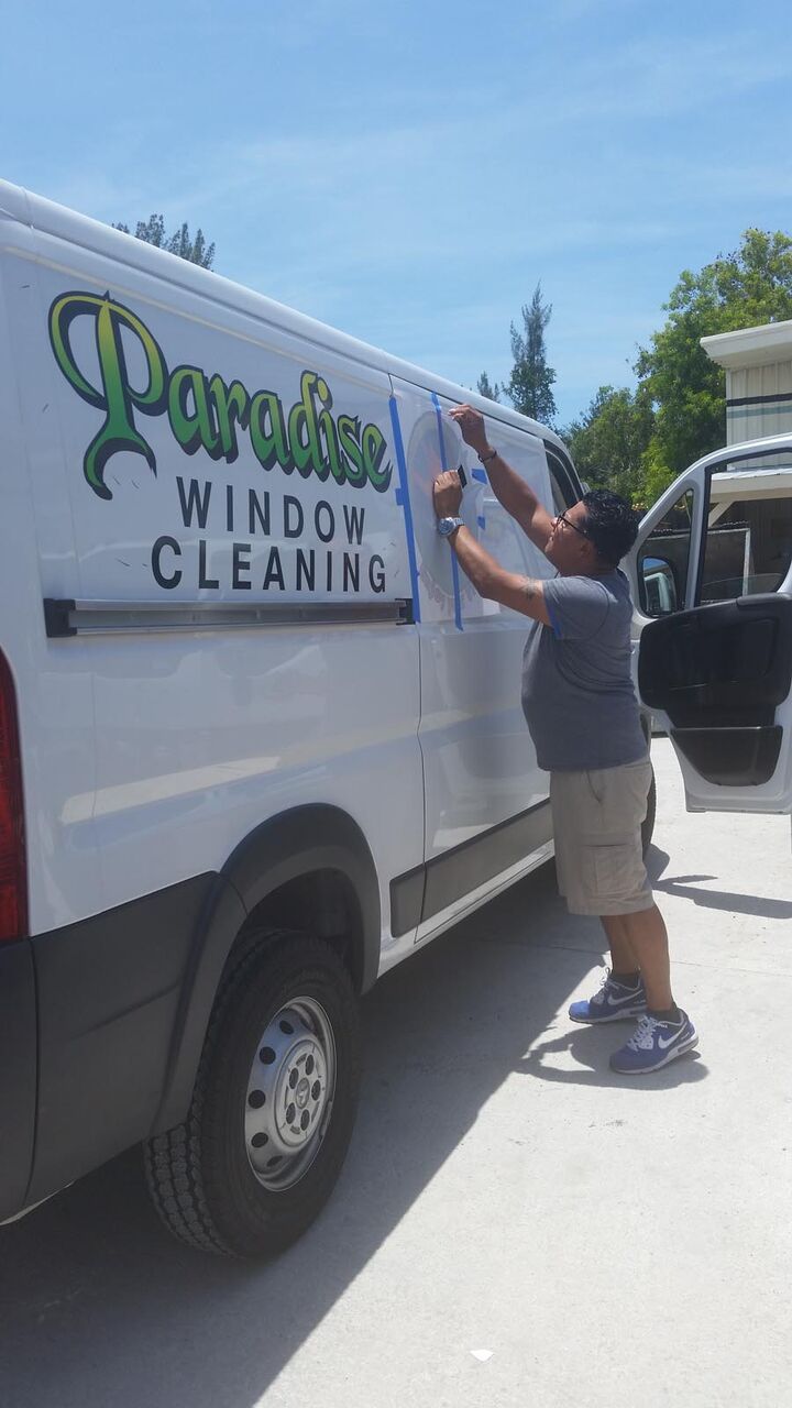 A man is standing next to a white van that says paradise window cleaning.
