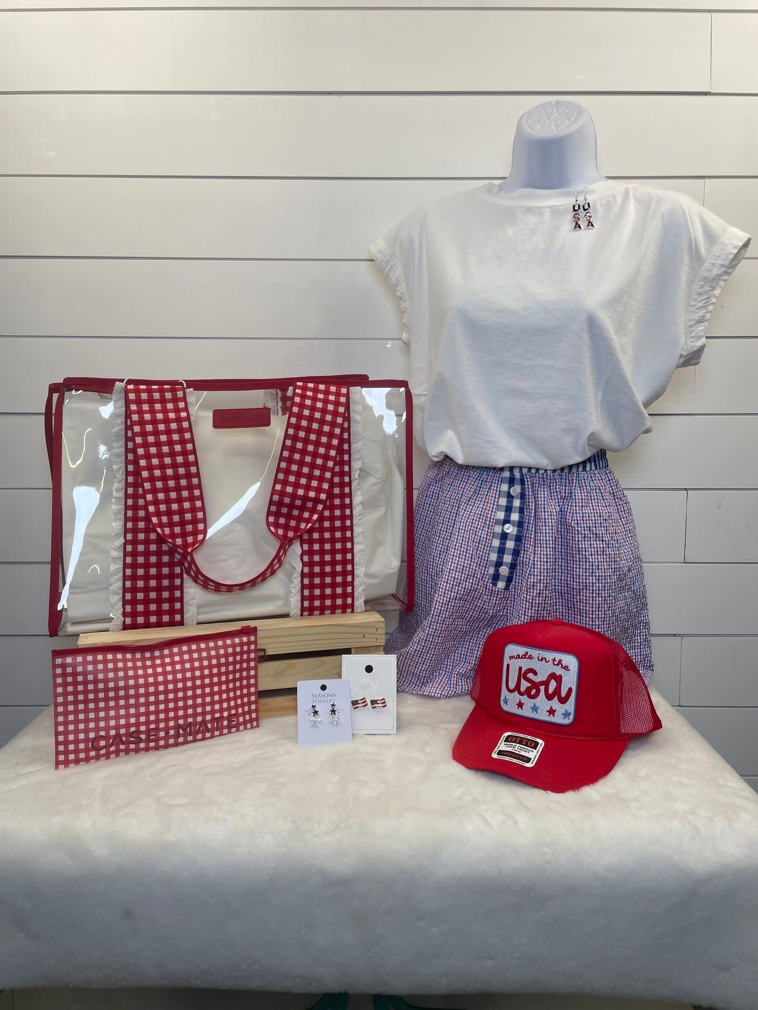 Red, white, and blue patriotic outfit set with tote bags, cap, and accessories on a white bench