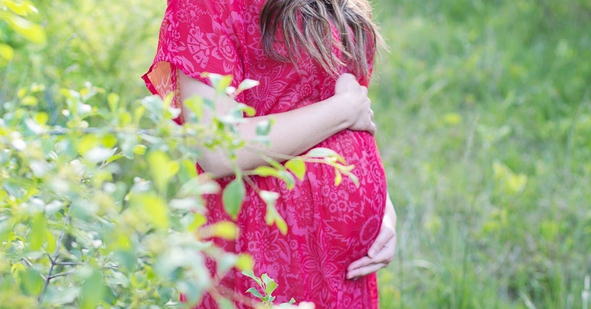 Pregnant mother dressed in pink cradling her baby bump
