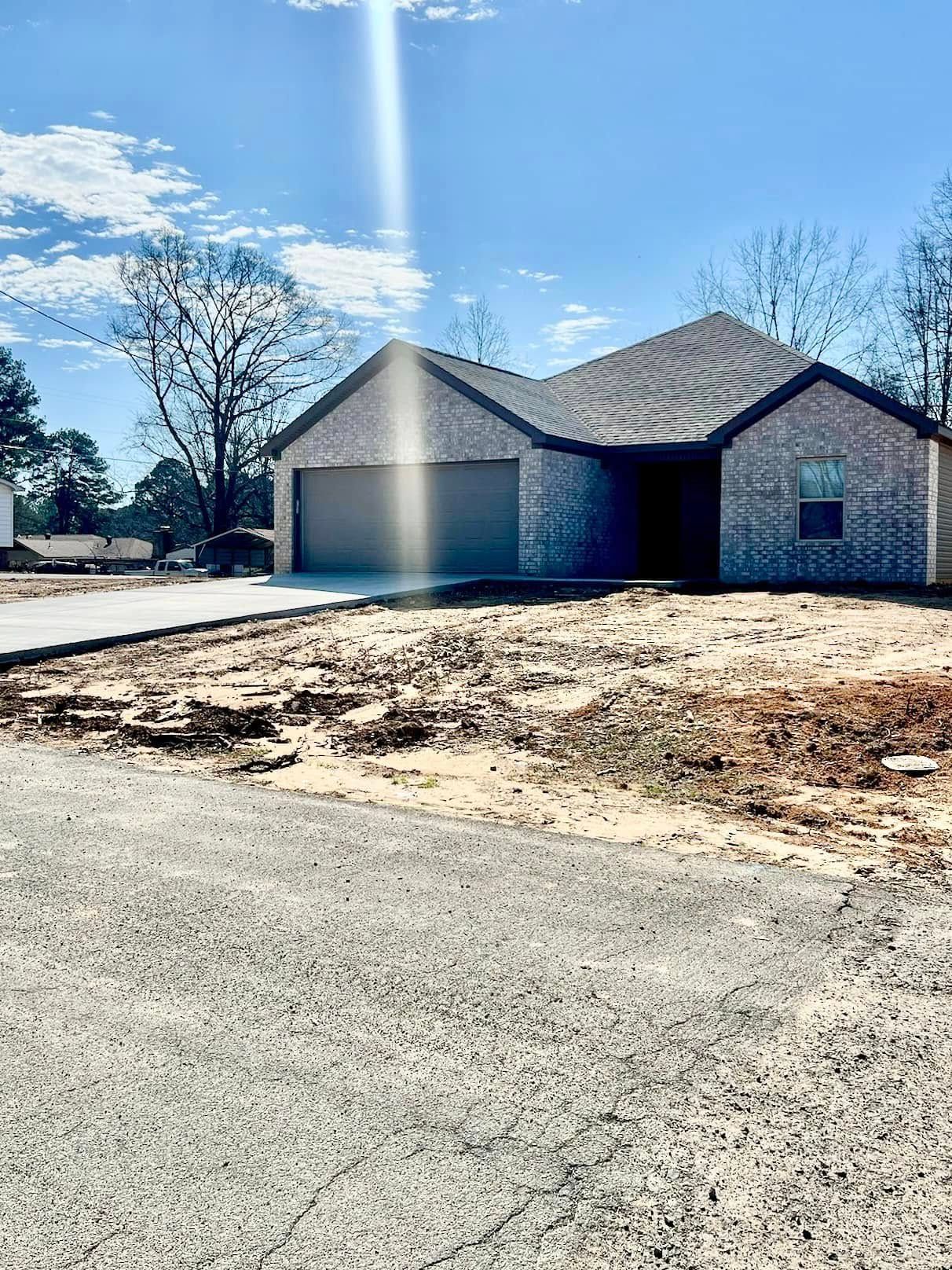 New brick house with a two-car garage under construction on a sunny day.