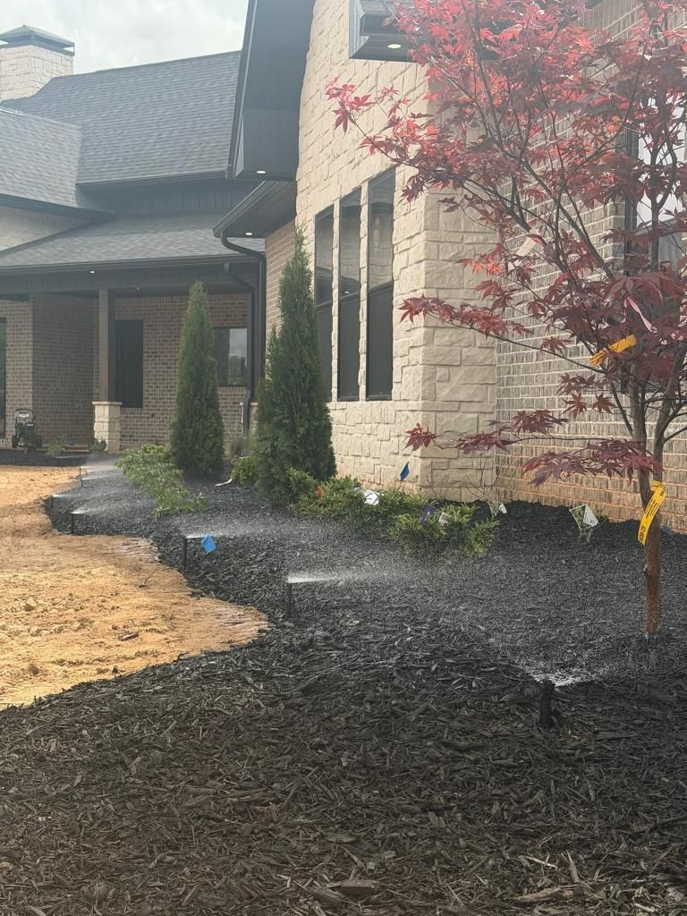 Front yard with gravel walkway, stone house, and red-leaf tree beside the entrance.