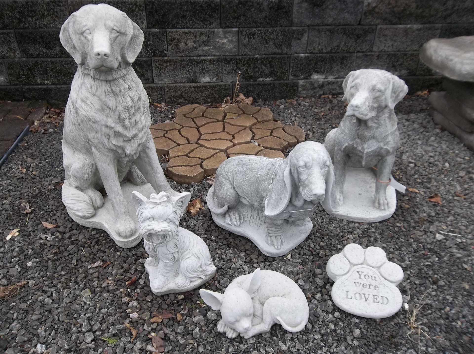 A group of concrete statues of dogs are sitting on the ground.