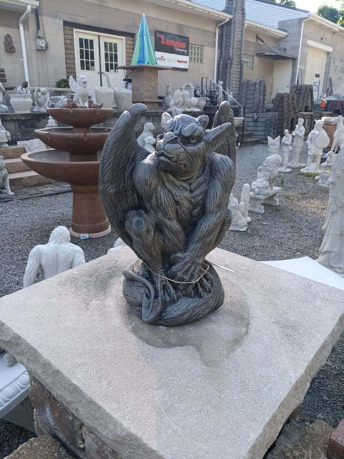 A gargoyle statue is sitting on top of a granite block.