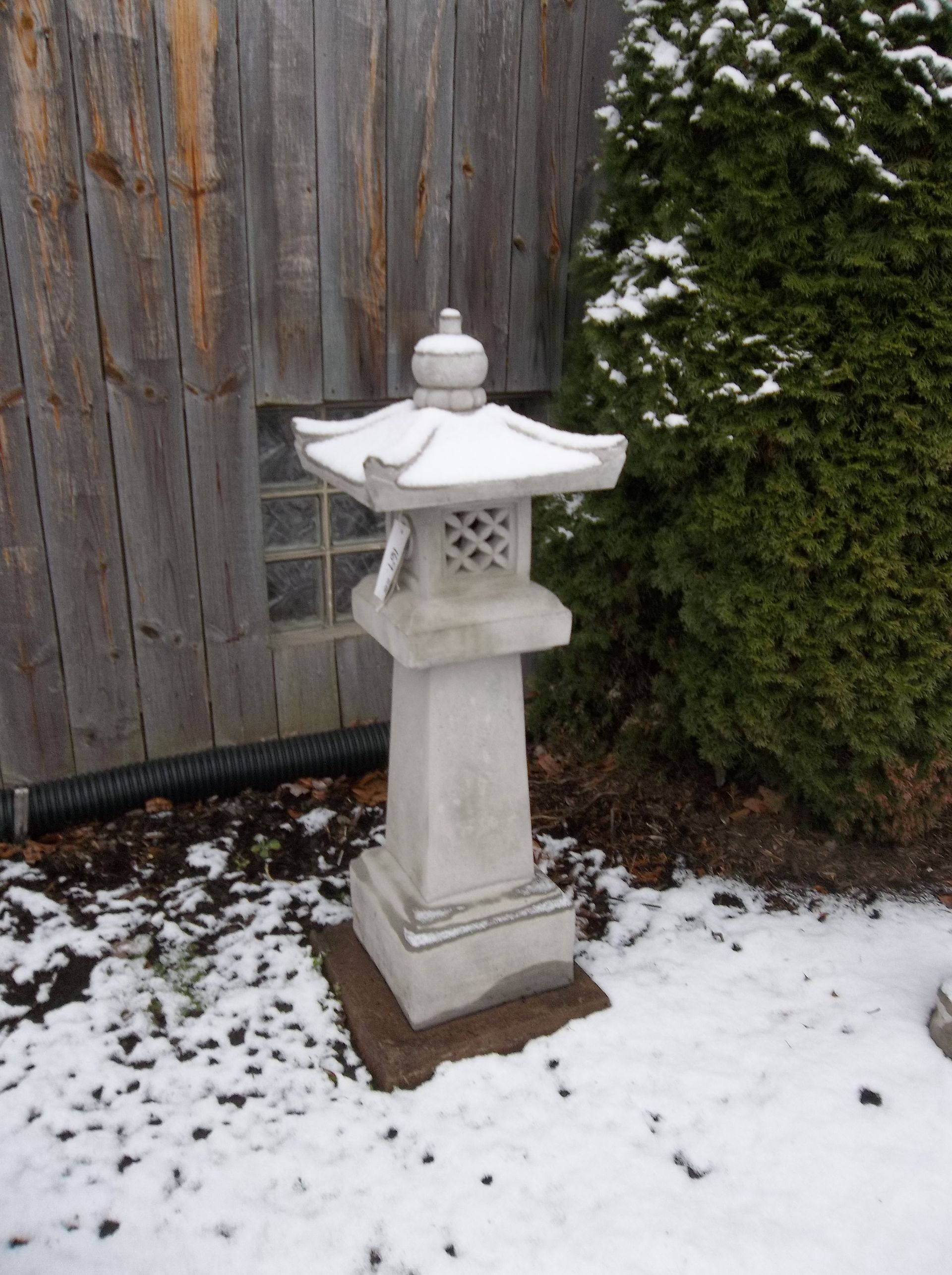 A statue in the snow with a wooden fence in the background
