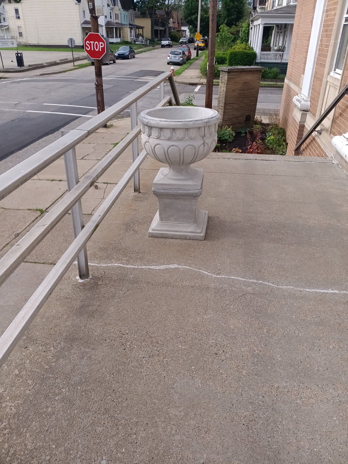 Decorative stone planter on a concrete ramp beside a stop sign in a residential neighborhood.