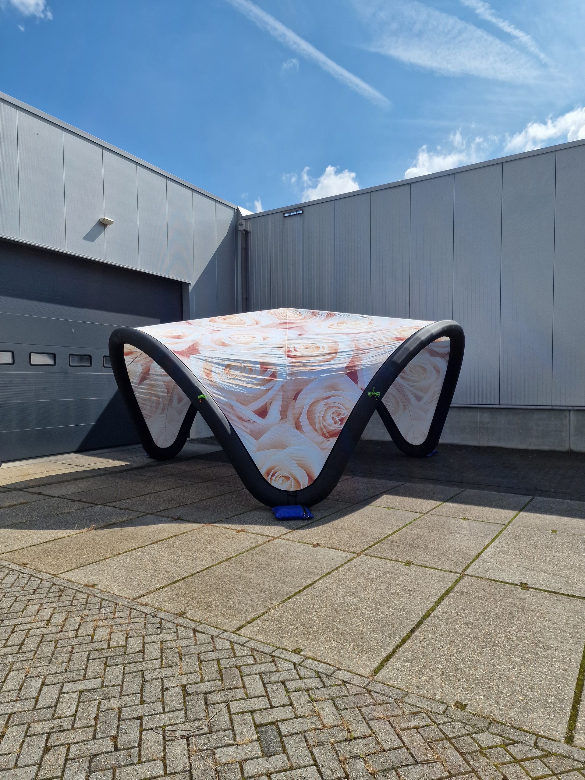 Een groot opblaasbaar object staat op een bakstenen stoep voor een gebouw.