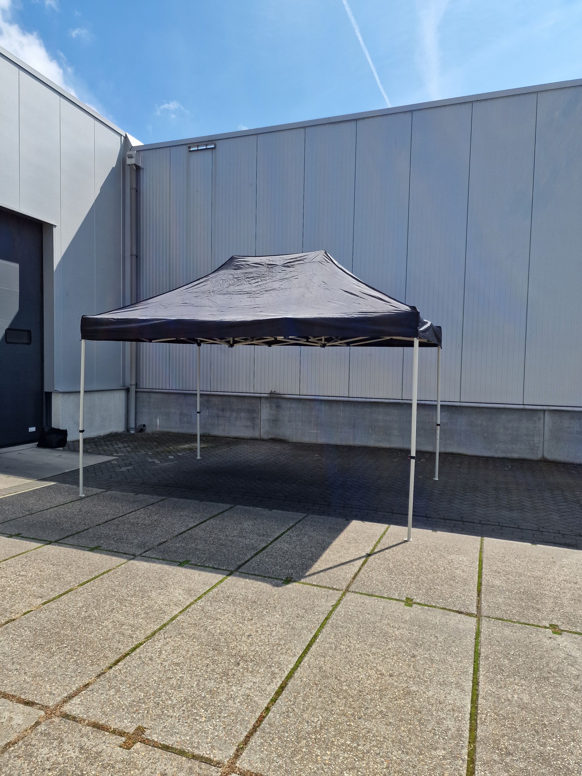 Een zwarte tent staat voor een gebouw.