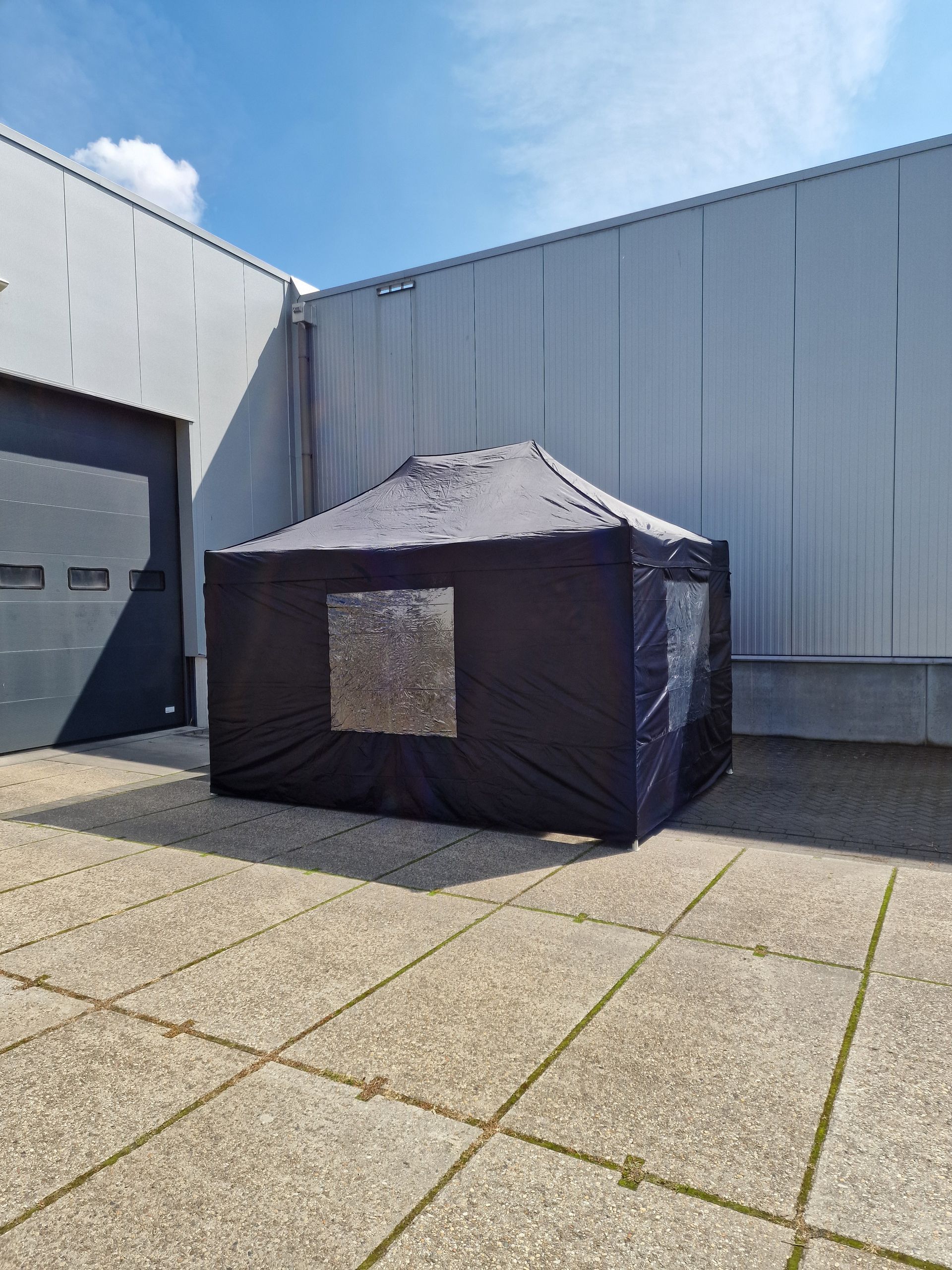 Een zwarte tent staat voor een gebouw.