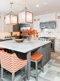 A kitchen with a large island , stools , and a stove.