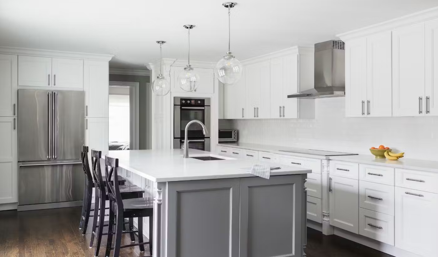 A kitchen with white cabinets , stainless steel appliances , and a large island.