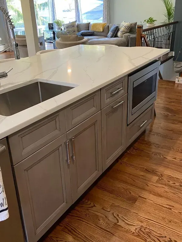 A kitchen with gray cabinets , a sink , and a microwave.