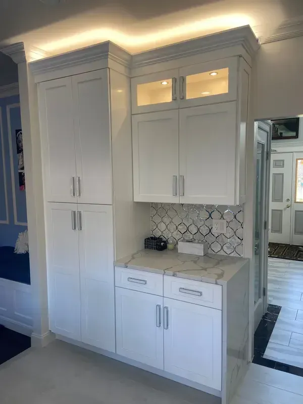 A kitchen with white cabinets and a marble counter top.