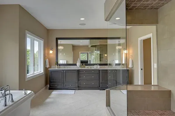 A bathroom with two sinks , a tub , and a large mirror.