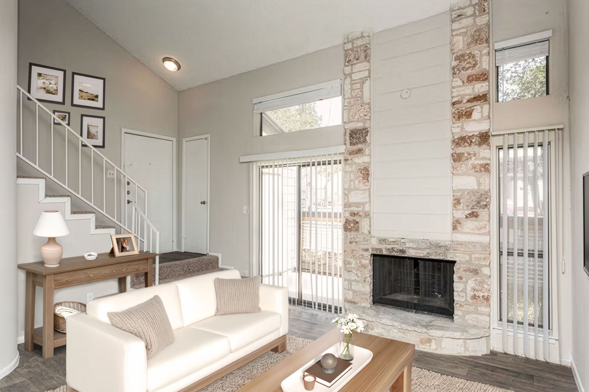 Bright living room with white sofa, fireplace, staircase, and tall windows in a neutral modern home
