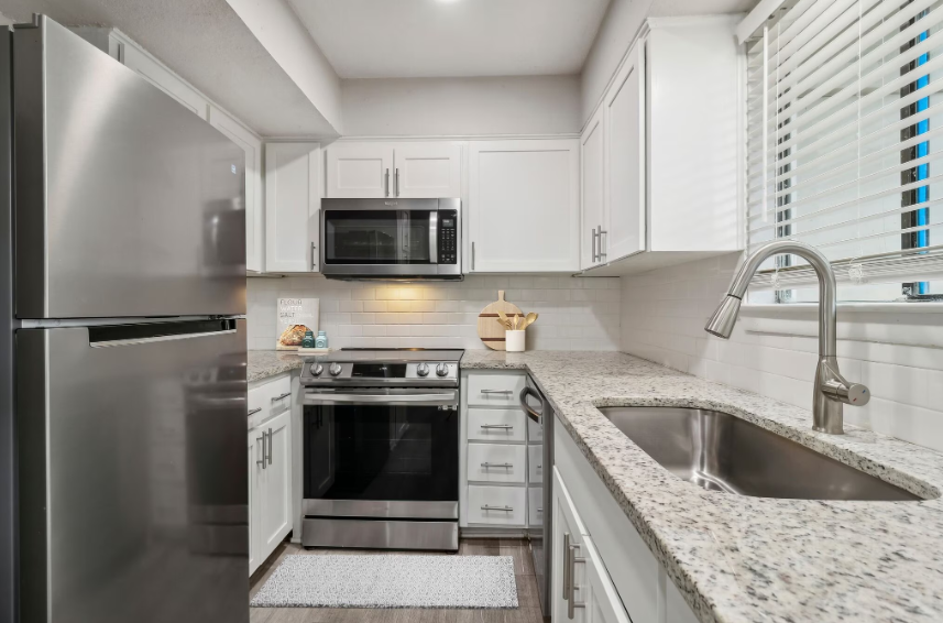 Bright modern kitchen with stainless steel appliances, white cabinets, and granite countertops