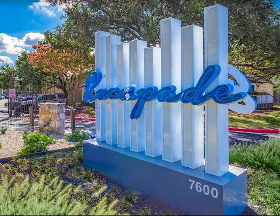 Blue “Bayside” sign with white pillars and address 7600 in a sunny landscaped entrance