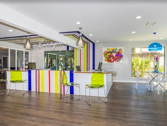 Bright modern cafe with colorful striped counter, lime chairs, wood floor, and patio seating