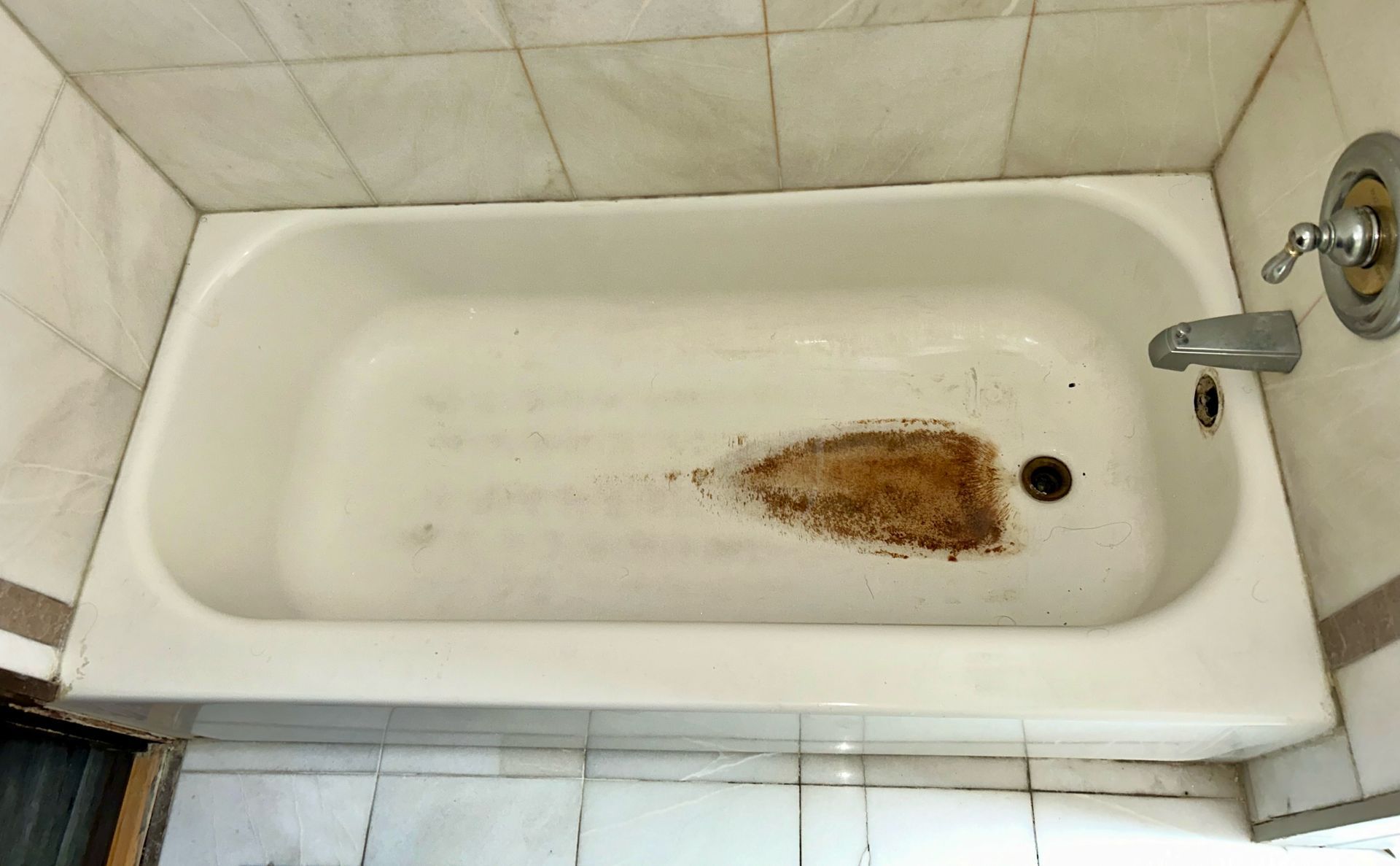 Here you can see a picture of a bathtub with a brown stain in the middle, that is in need of bathtub restoration, which can be done by Ohio tub pros. 