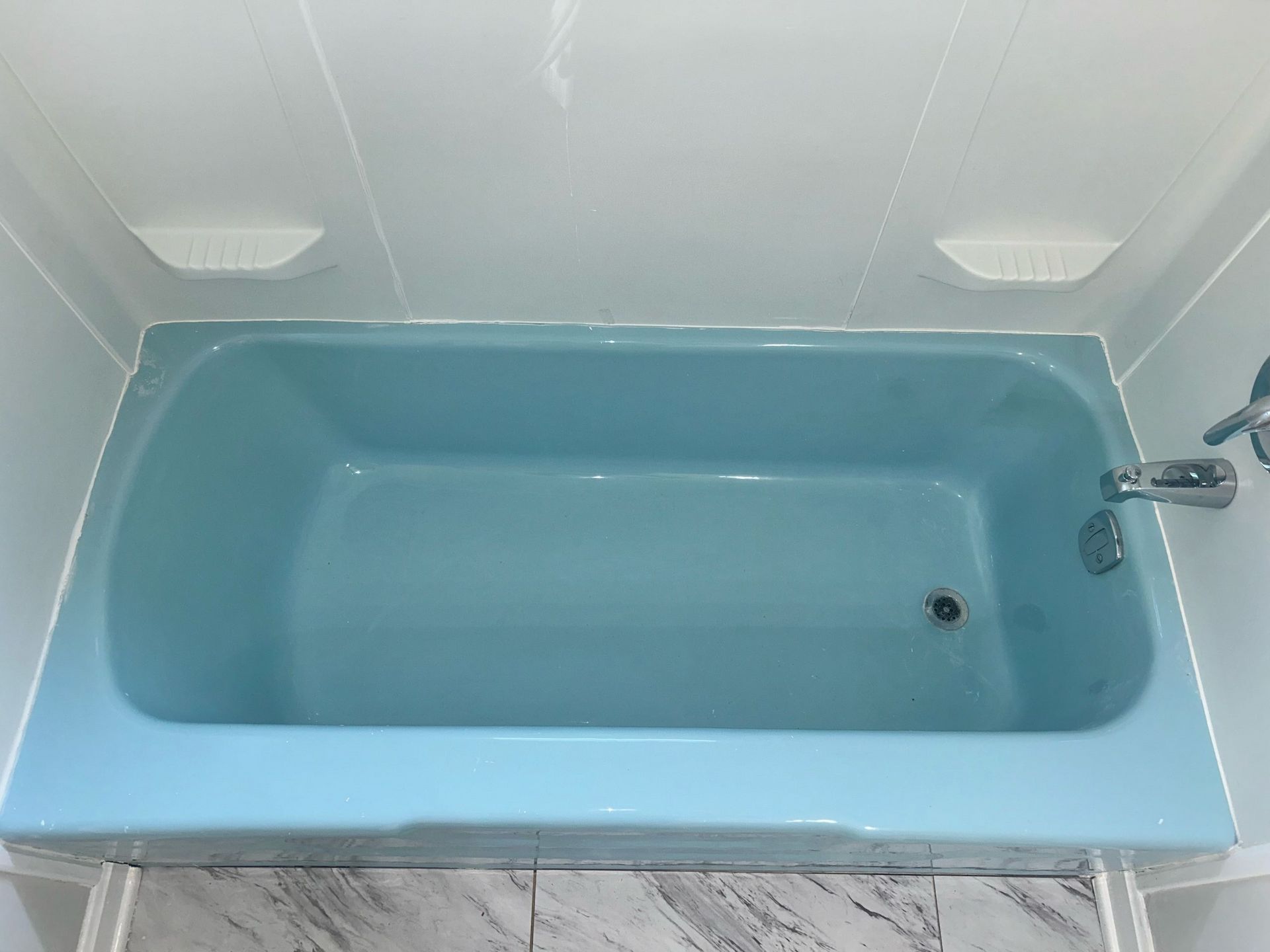 Picture of a blue tub that looks kind of outdated. When you want to transform your tub at a fraction of the cost of a complete bathroom remodeling, think about doing a bathtub refinishing with Ohio tub pros, which can make a tremendous difference and make your bathroom look much better! 