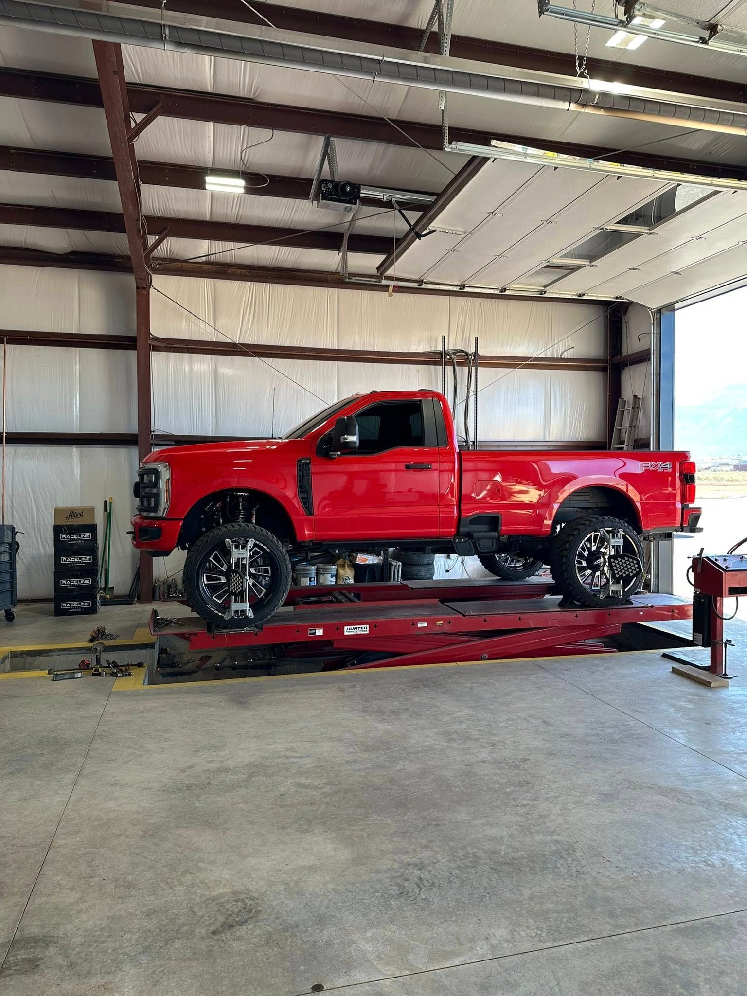 Red pickup truck on a lift inside a garage.