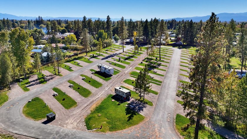 Aerial view of RV campground with parked trailers on dirt lots surrounded by green grass.