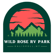 Logo for Wild Rose RV Park in Kalispell, MT. Features mountains, sunset, and trees in a green and red color scheme.