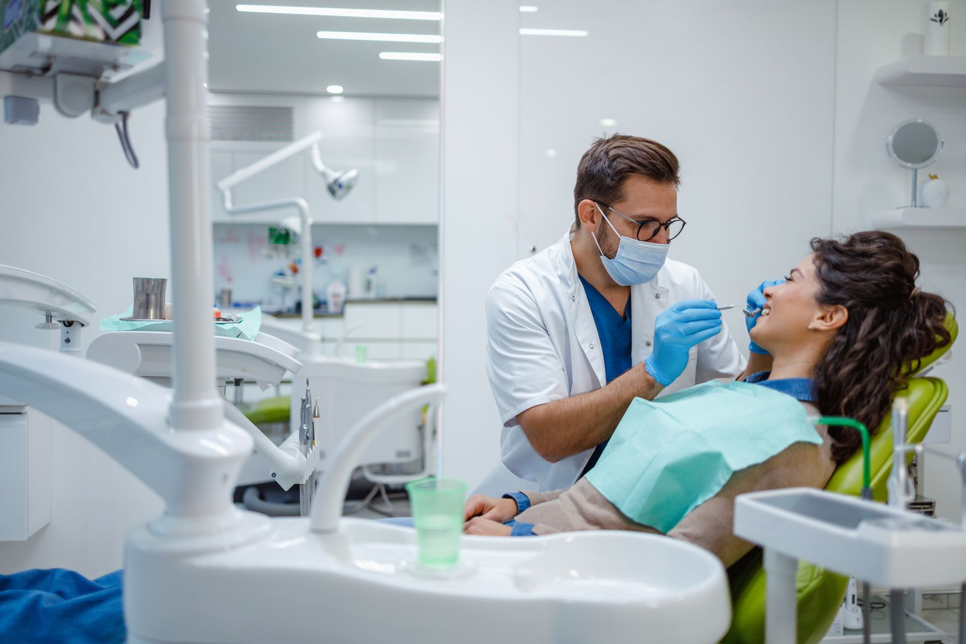 Una donna è seduta sulla poltrona del dentista mentre un dentista le esamina i denti.