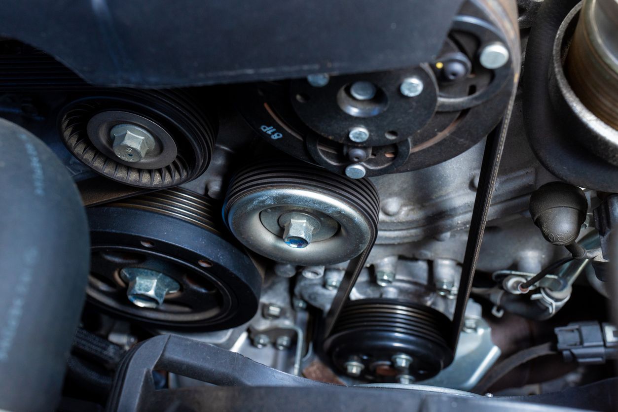 A close up of a car engine with belts and pulleys