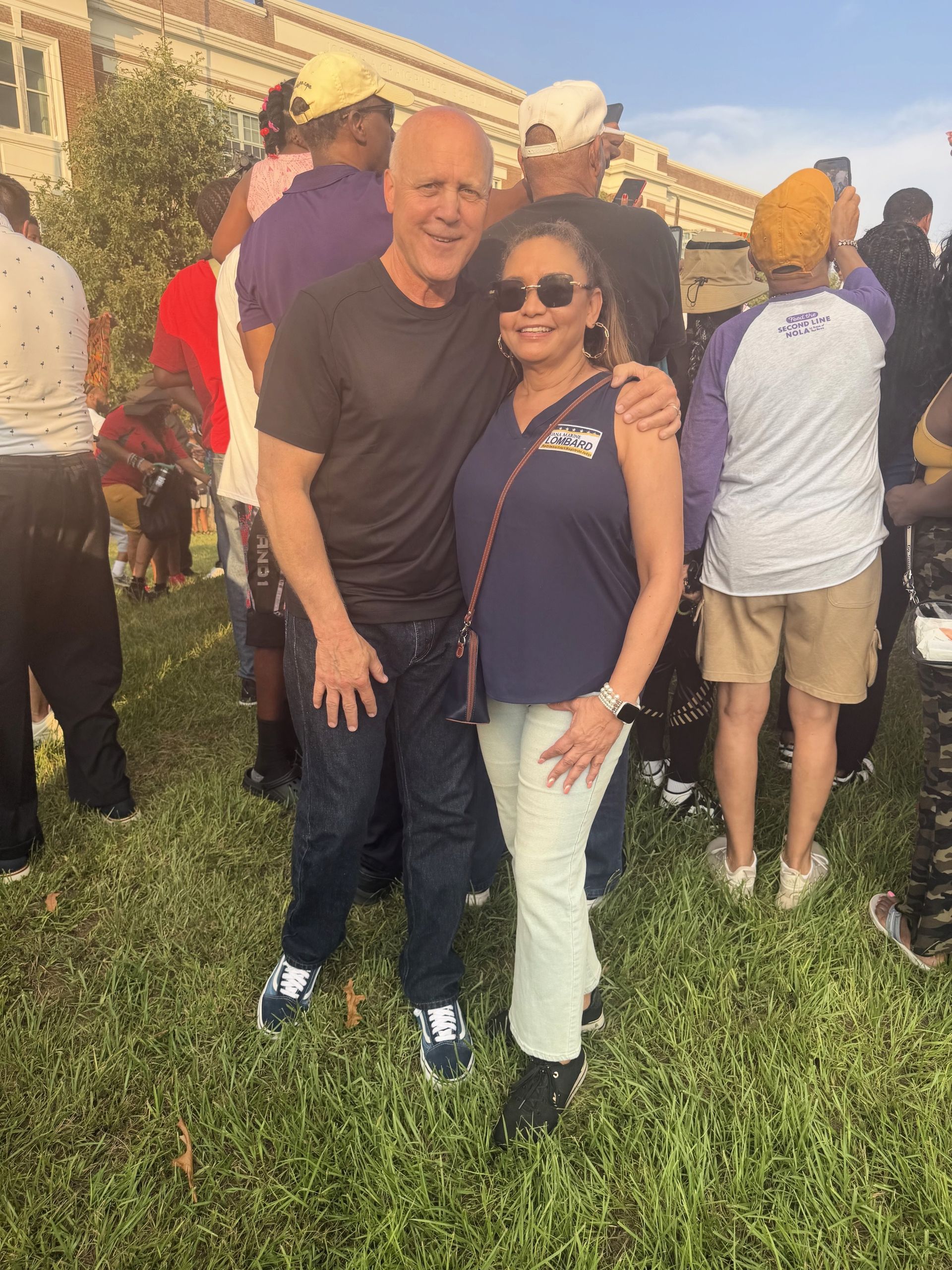 Two people smiling and posing together on a grassy lawn at an outdoor event.