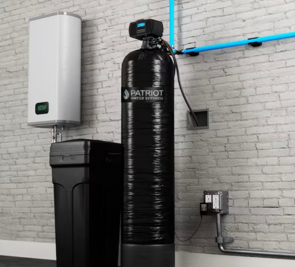 A water filtration system with a sediment filter and a large black tank connected by blue piping against a brick wall.