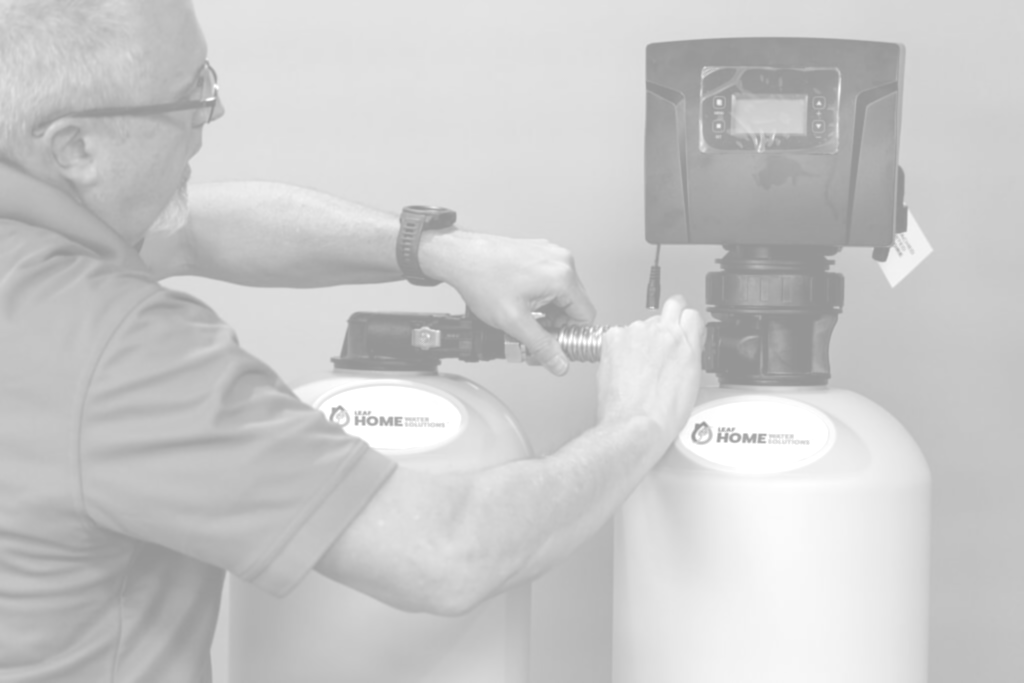 A technician connects a pipe between two water treatment tanks with digital control valves.