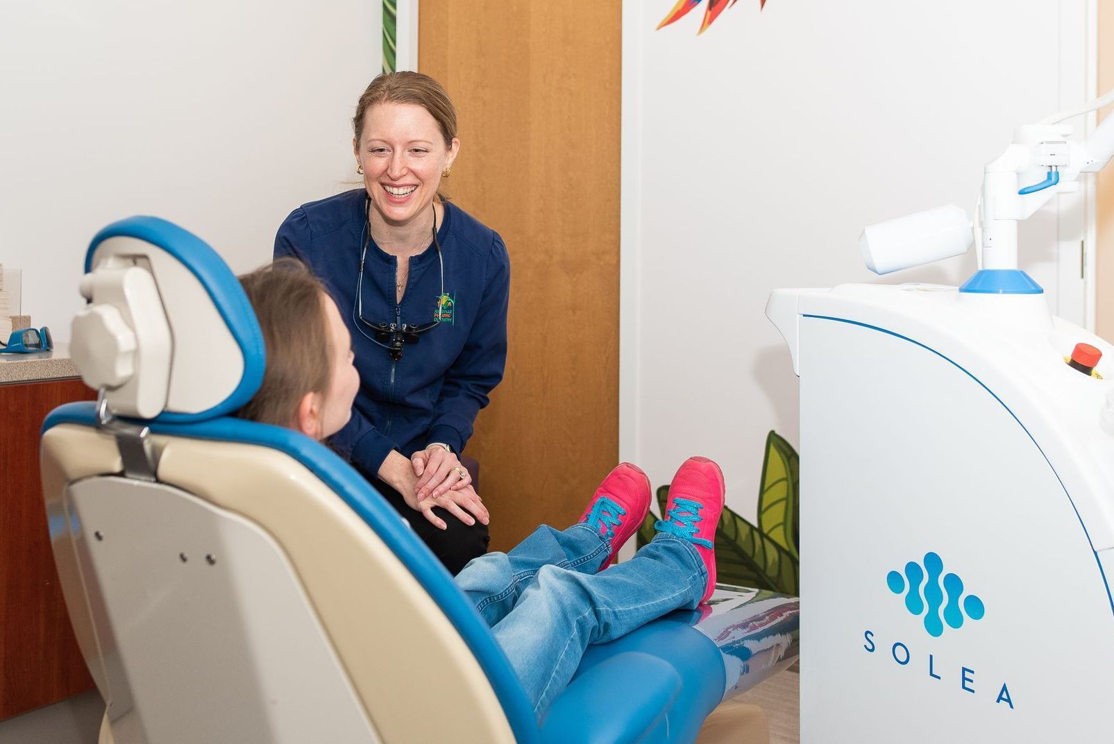 A dentist is talking to a young boy in a dental chair. Asheville Pediatric Dentistry (828) 277-6788