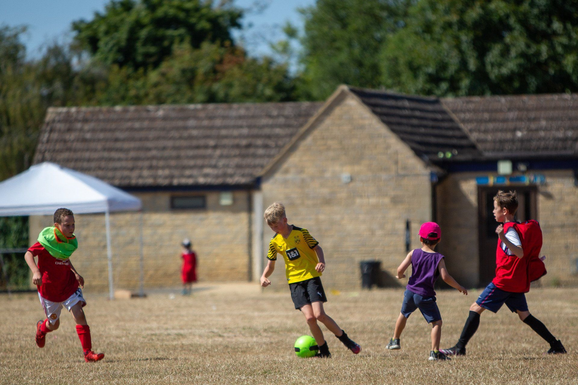Teenage girl running with soccer ball on a playing field during the match and about to kick the ball