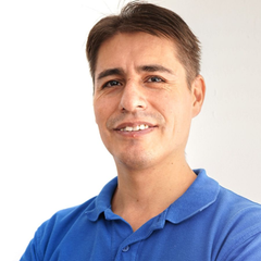 Uomo sorridente con indosso una polo blu su sfondo bianco