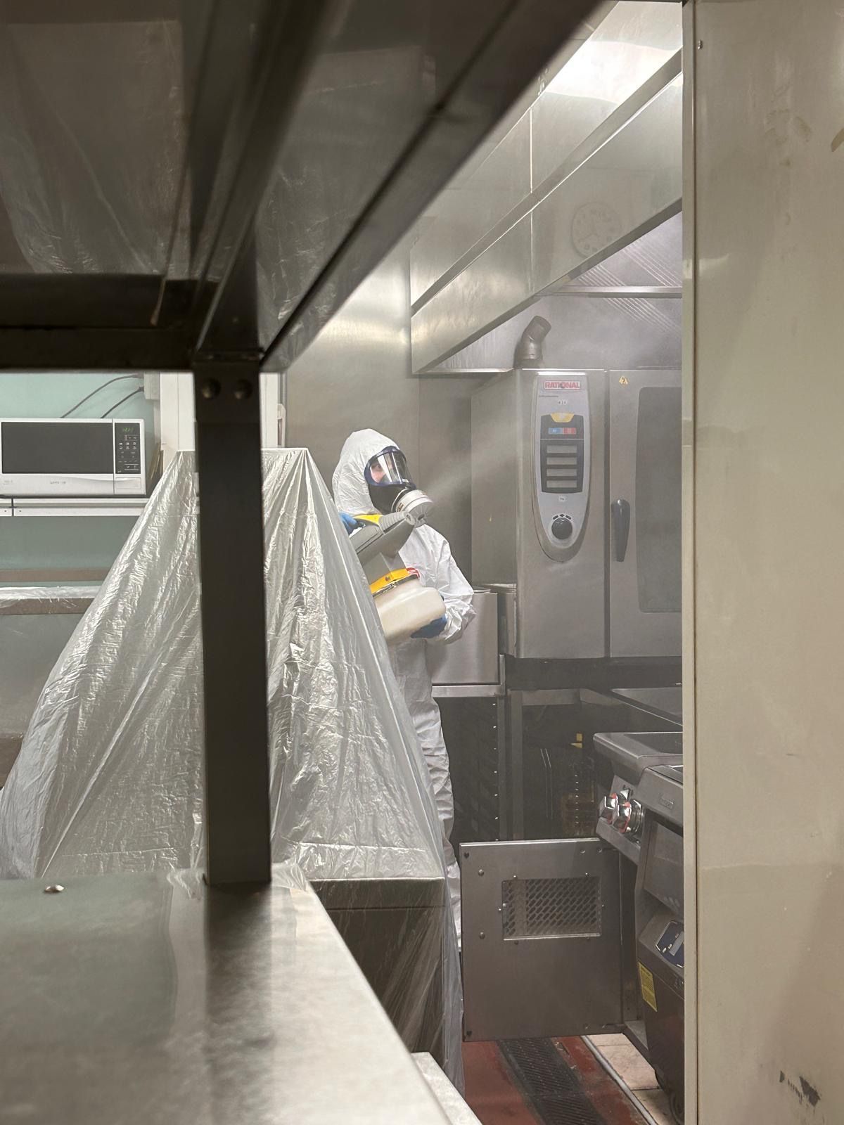 Operaio con tuta protettiva all'interno di una cucina industriale coperta o di un'area di lavorazione.