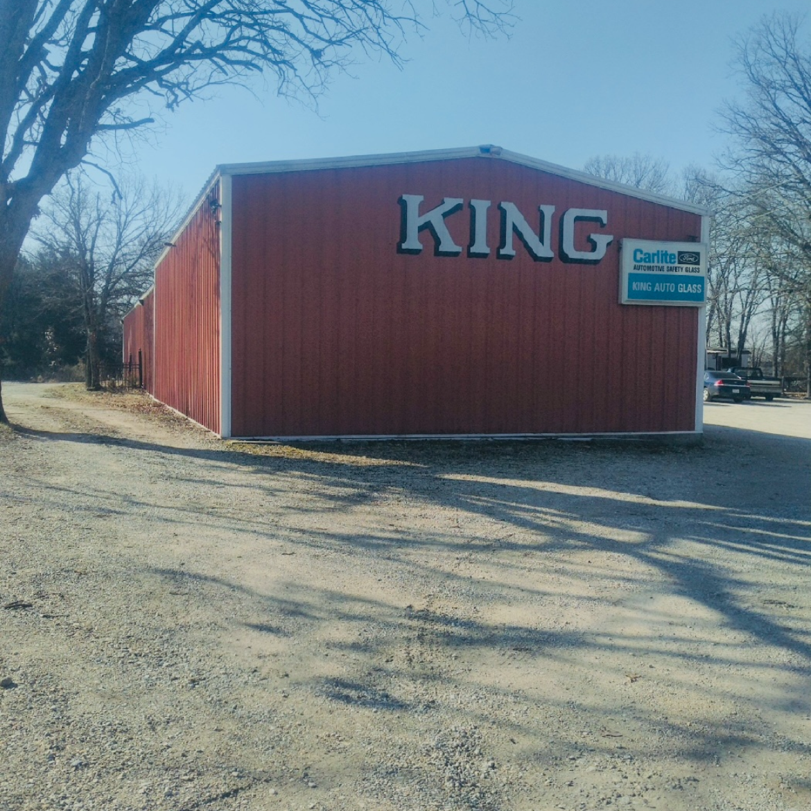Red building with large KING sign on a gravel lot, under a clear blue sky.