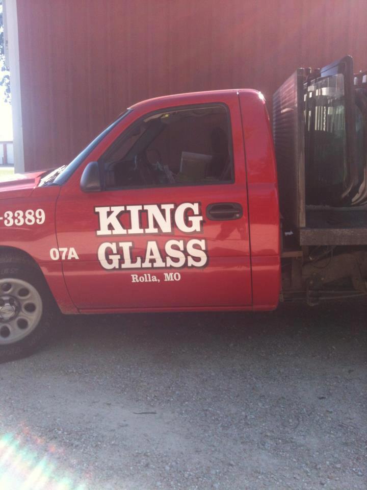 Red King Glass service truck parked beside a maroon wall, with company logo and text on the door.