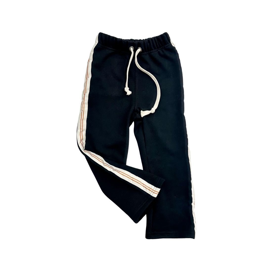 Pantalones deportivos negros con rayas laterales blancas y cordón ajustable sobre fondo blanco.