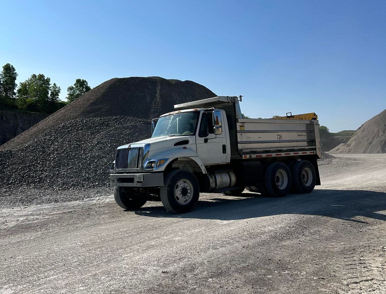 A dump truck is parked in front of a pile of gravel.