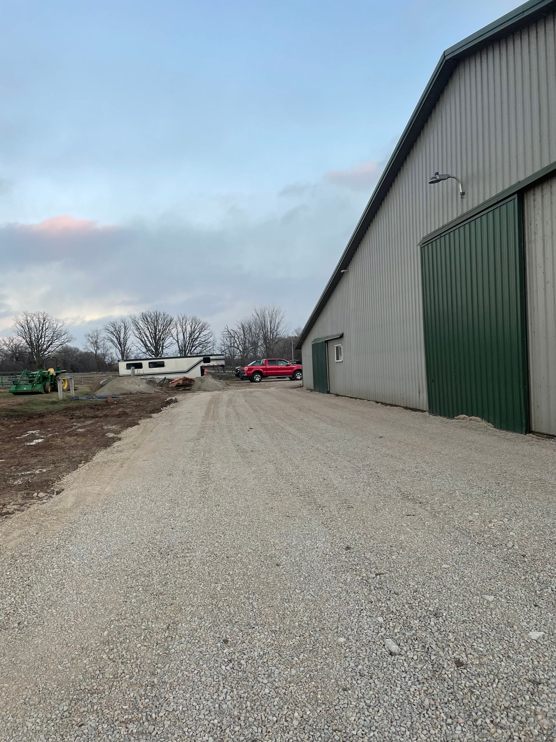 A gravel road leading to a large building with a green door.