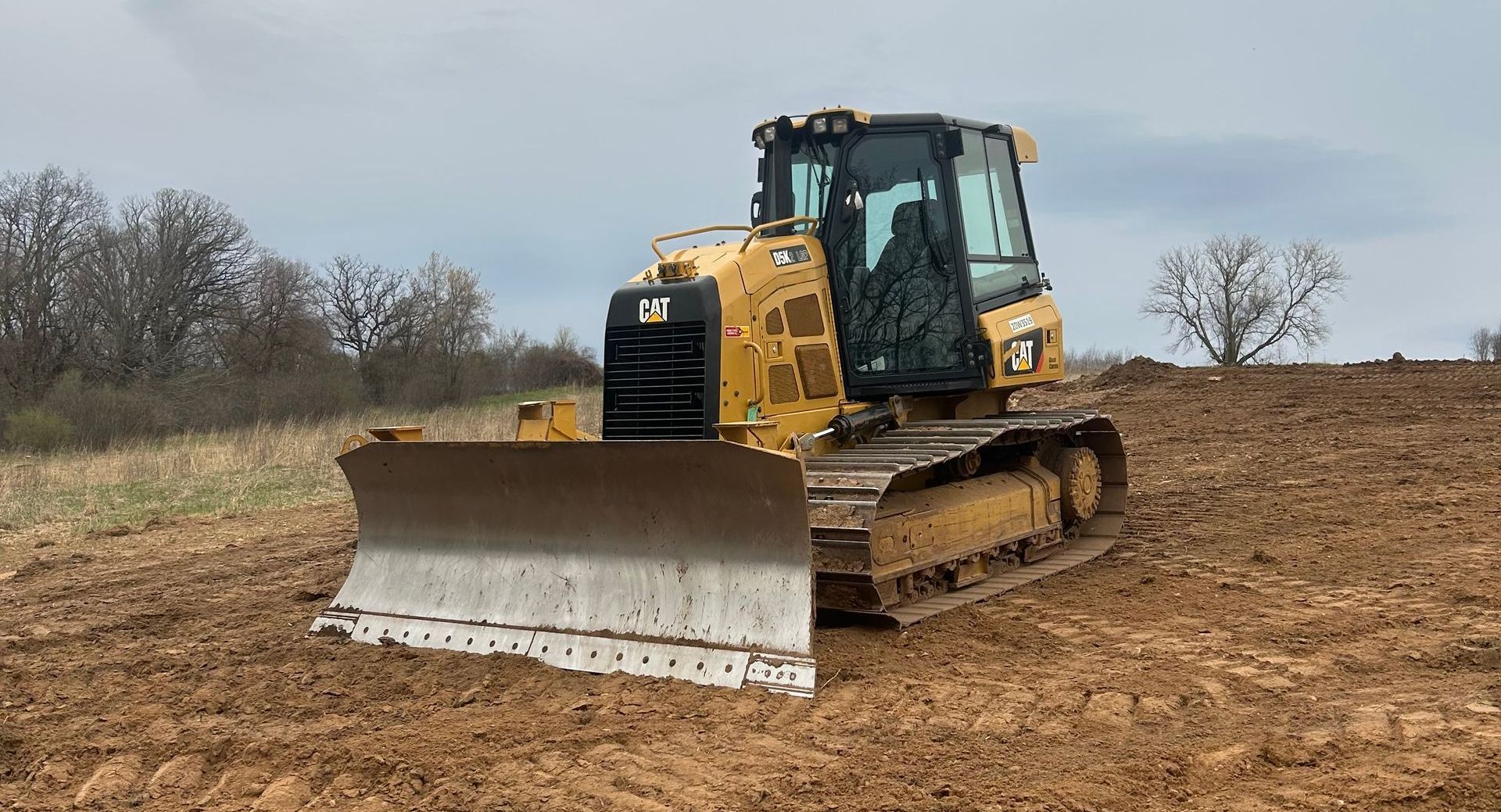 A bulldozer is driving through a dirt field.
