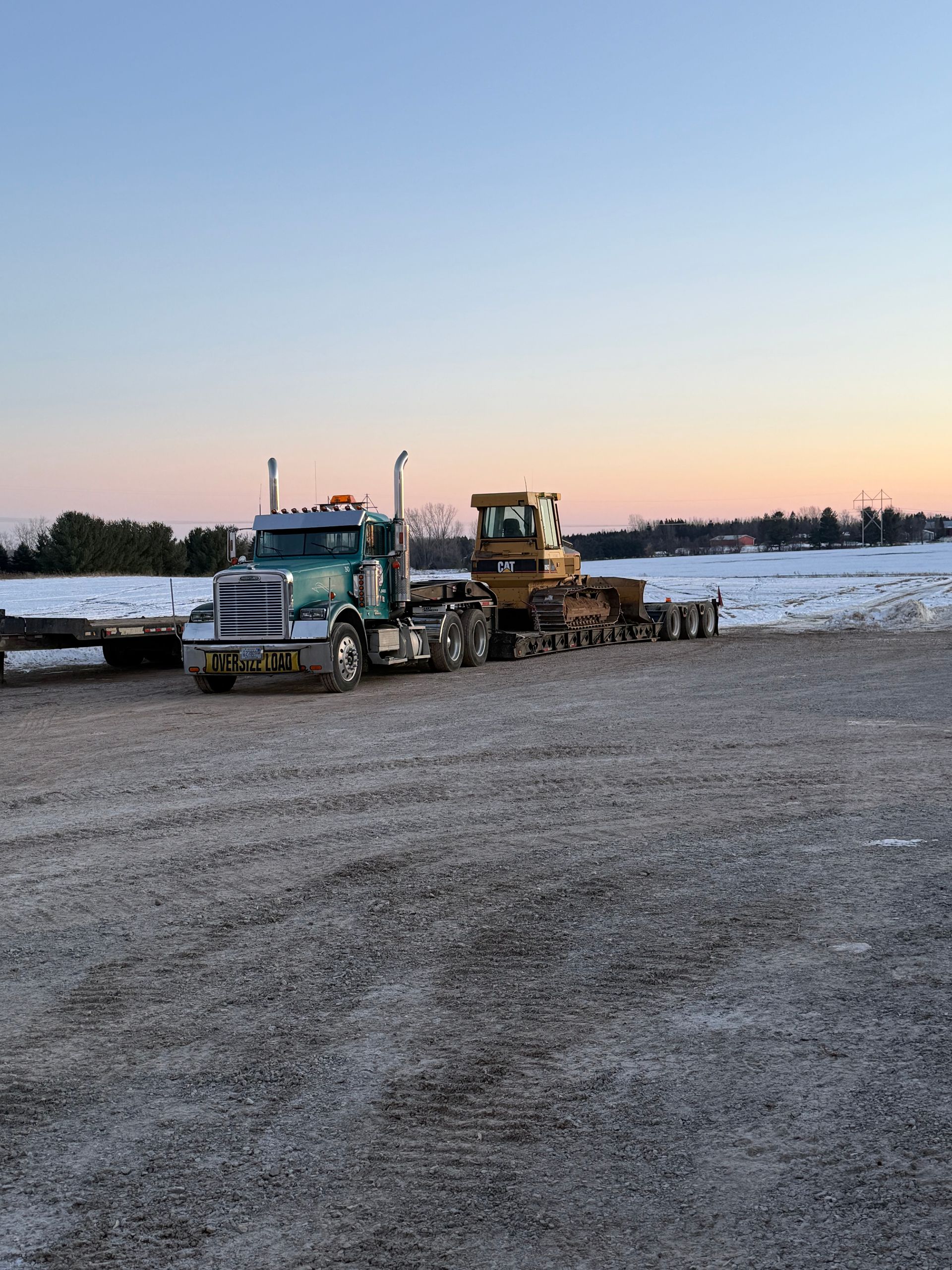 A red dump truck is driving down a dirt road.