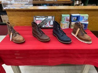 Four boots on a red table. Various brown leather boots are on display at a store.