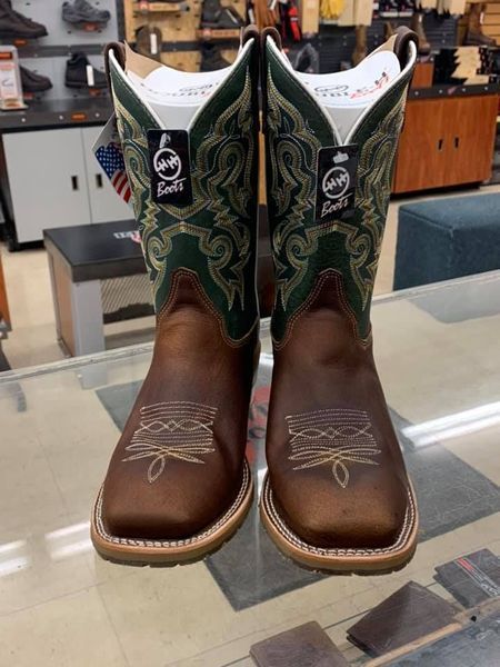 Pair of brown cowboy boots with green and gold stitching, on display in a store.