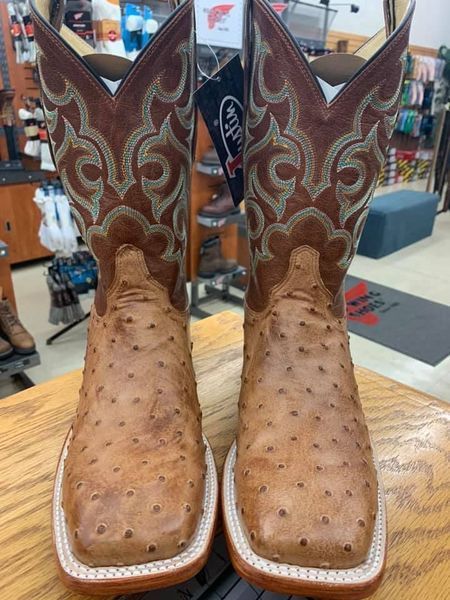 Pair of brown ostrich cowboy boots with decorative stitching and square toes, on display.